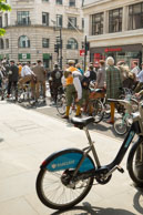 Boris Bike / Tweed Run riders passing a parked Boris Bike on Cheapside