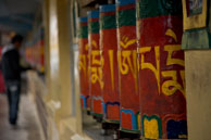 Prayer wheels at Dharamsala / Colourful prayer wheels at Dharamsala with a worshipper spinning them in the background