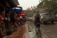 Cyclist being soaked / Religious procession for Lao New Year in Luang Prabang and following celebrations