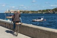 Shall I fish? / Cuban man on his bicycle with this fishing rod at Havana harbour