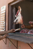 Buying Pork / A Cuban butcher is taking payment for a piece of pork under the head of a pig in Trinidad