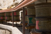 Line of prayer wheels / Long line of prayer wheels stretch along the wall of the monastery